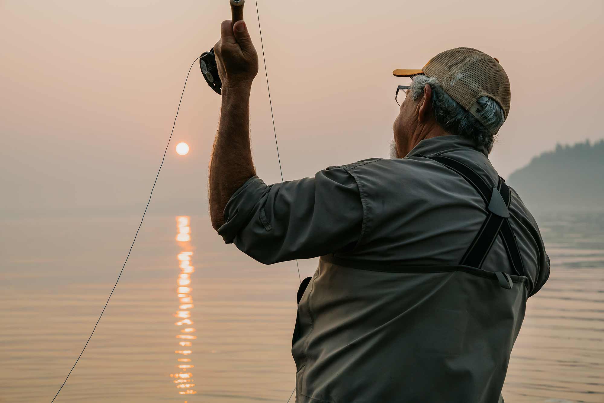 senior male fly fishing at sunrise
